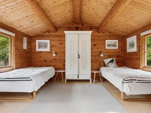 Uma cabana com duas camas, um guarda-roupa e quadros nas paredes.
