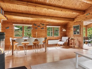 A wooden cabin interior with a dining area, chairs, a table, and a fireplace. - "Greta" - 1.7km from the sea by Interhome (Rørvig)