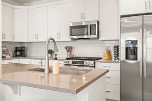 A modern kitchen with white cabinets, stainless steel appliances, and a granite countertop. - Desert Oasis - Pool, Hot Tub and Pickleball Courts (Washington)