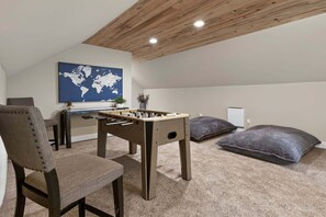 A cozy room with a foosball table, a chair, a world map on the wall, and a bed with pillows. - Brand New Home @ Lake Granby w/4 Bedrooms & 2 Living Rooms (Grand Lake)
