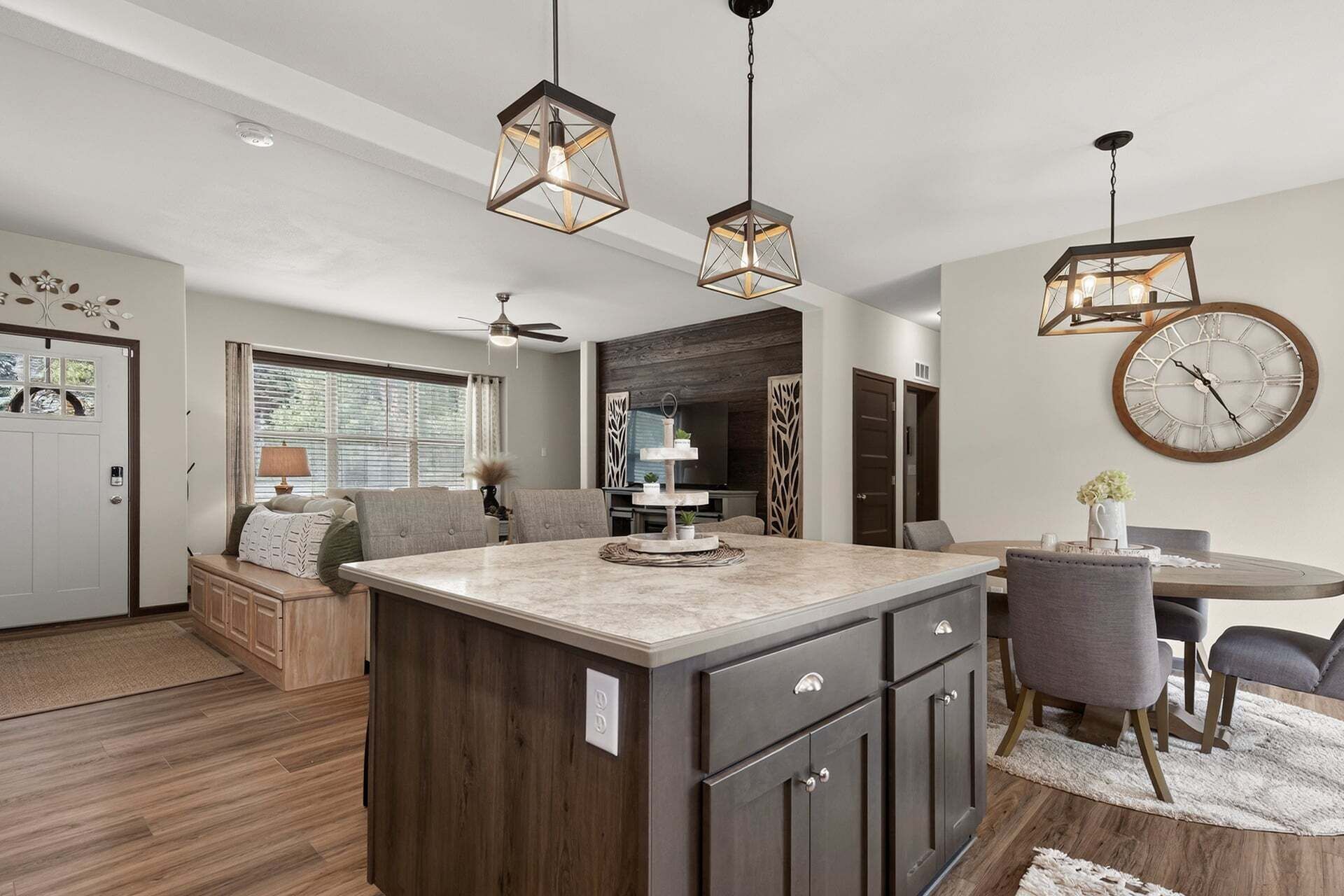 A modern kitchen with a central island, pendant lighting, and a dining area with a round table and chairs.