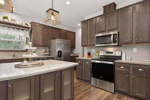 A modern kitchen with dark wood cabinets, stainless steel appliances, and a marble countertop. - Brand New Home @ Lake Granby w/4 Bedrooms & 2 Living Rooms (Grand Lake)