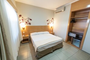 Une chambre d’hôtel comprenant un lit, des tables de chevet, une armoire et un appareil de climatisation.