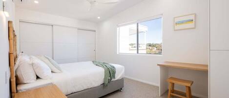 Une chambre à coucher avec un lit, un bureau, une fenêtre et un ventilateur de plafond.