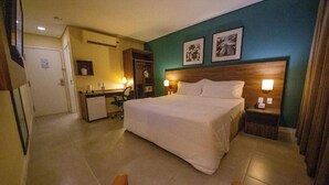Une chambre d’hôtel avec un grand lit, un bureau avec une chaise, une armoire et deux lampes de chevet.