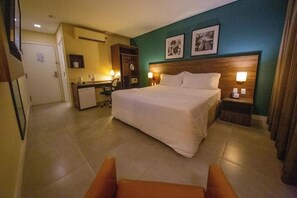 A hotel room with a large bed, a desk with a chair, a wardrobe, and two bedside lamps. - Rooftop Evenings, Poolside Days & Comfortable City Stays (Acre)