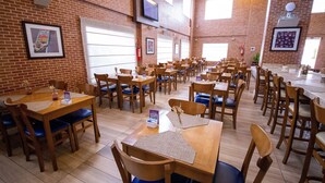 Un restaurant aux murs de briques, aux tables en bois et aux chaises rembourrées de tissu bleu.