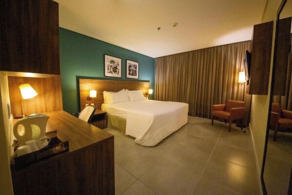 A hotel room with a bed, bedside tables, a desk, a chair, and a television. - Rooftop Evenings, Poolside Days & Comfortable City Stays (Acre)