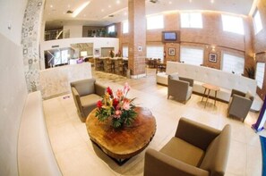 A spacious lobby with a round wooden coffee table, seating area, and a view of the kitchen and dining area. - Rooftop Evenings, Poolside Days & Comfortable City Stays (Acre)