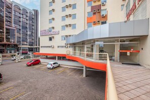Un hotel de diseño moderno, con un paseo cubierto y un aparcamiento con varios coches.