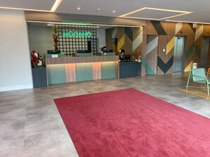 Ein Empfangsbereich im modernen Design mit einer Rezeption, einer Neonreklame und einer Wand mit Musterung.
