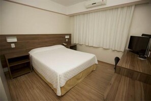 Ein Hotelzimmer mit Bett, Nachttisch, Fernseher und Klimaanlage.