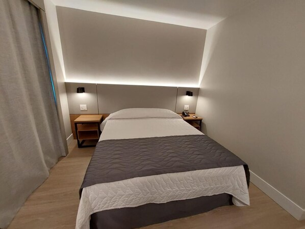 Ein Hotelzimmer mit einem Bett, Nachttischen und einem Kopfteil.