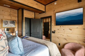 Una habitación acogedora con una cama, un cuadro y un televisor montado.