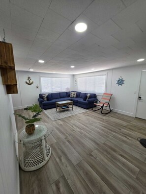 Ein Wohnzimmer mit einem Ecksofa, einem runden Couchtisch und einem Schaukelstuhl.