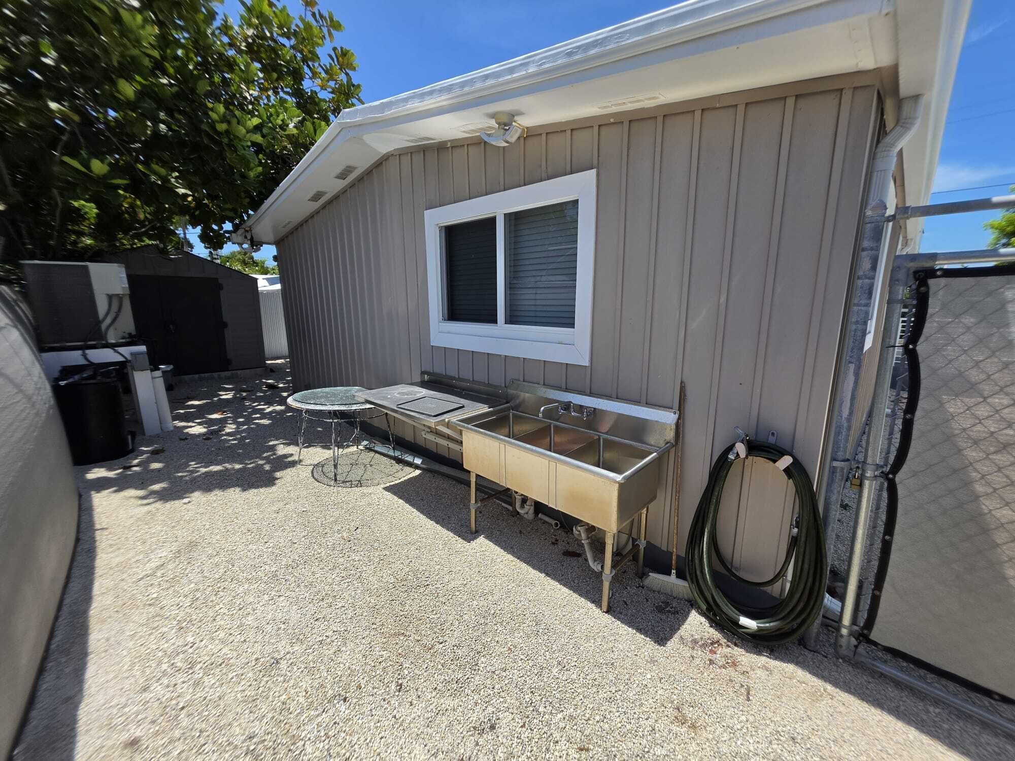 A residential building with a window, a metal table, and a hose.