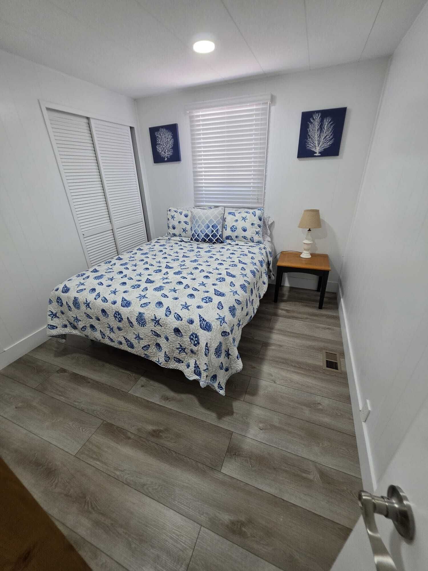 A bedroom with a bed, a nightstand, a lamp, and two wall art pieces.