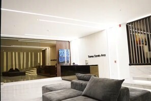 A modern hotel lobby with a reception desk, a large flat-screen TV, and a seating area with sofas. - Modern Apt. with Skyline Views - Easy 5-Min Drive to Center (Cuenca)