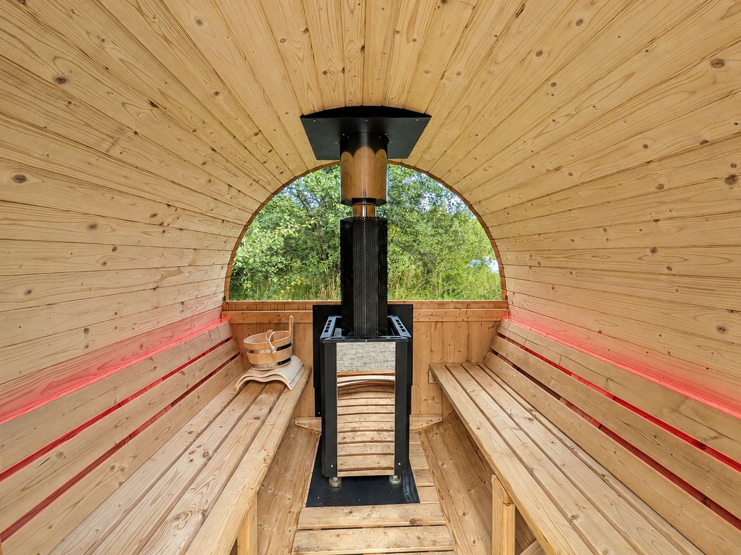 A sauna with wooden benches and a central heating unit.