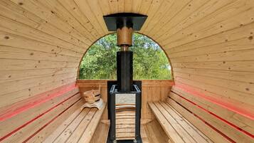 A sauna with wooden benches and a central heating unit.
