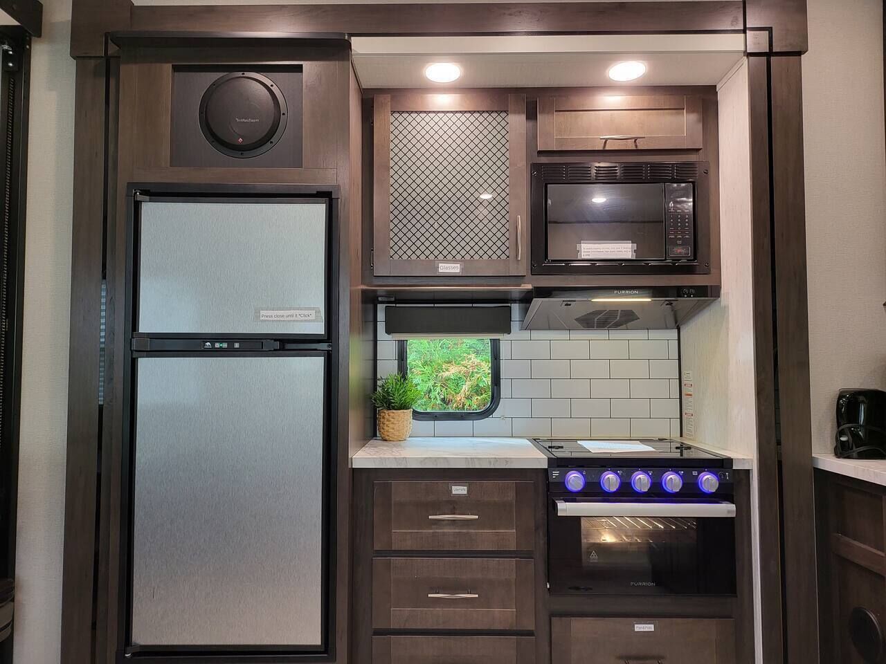 Eine kompakte Küche mit Kühlschrank, Mikrowelle, Backofen und einem Fenster mit Ausblick.