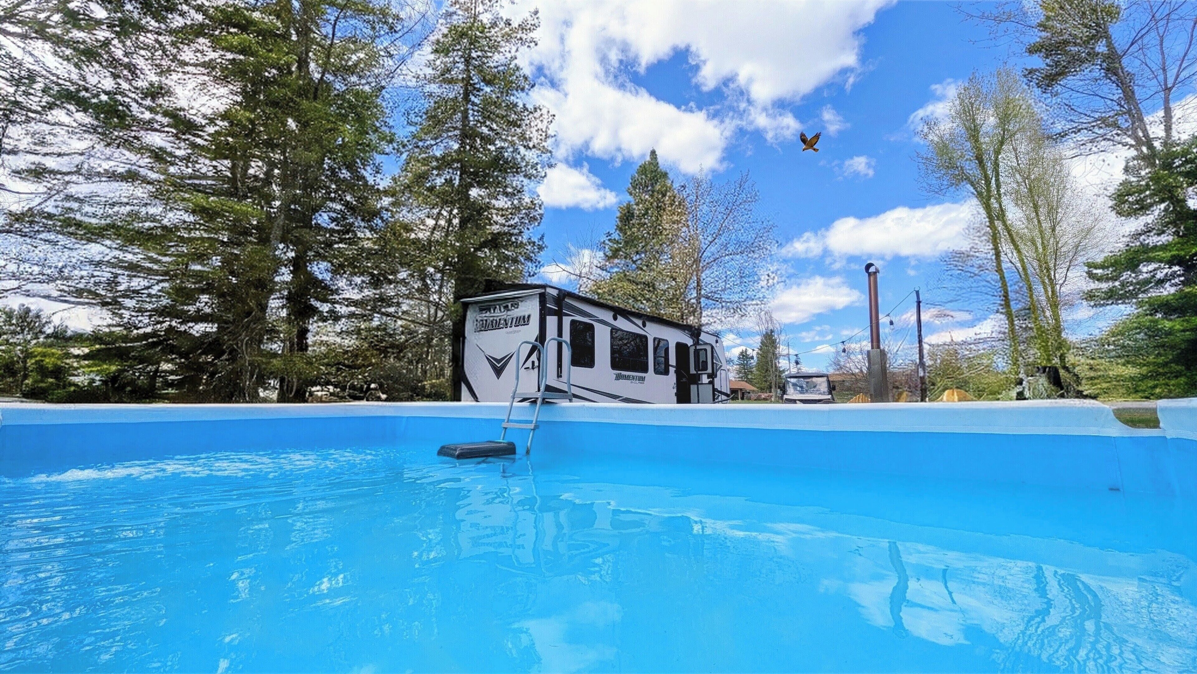 Ein Campingplatz mit Schwimmbad, umgeben von Bäumen.