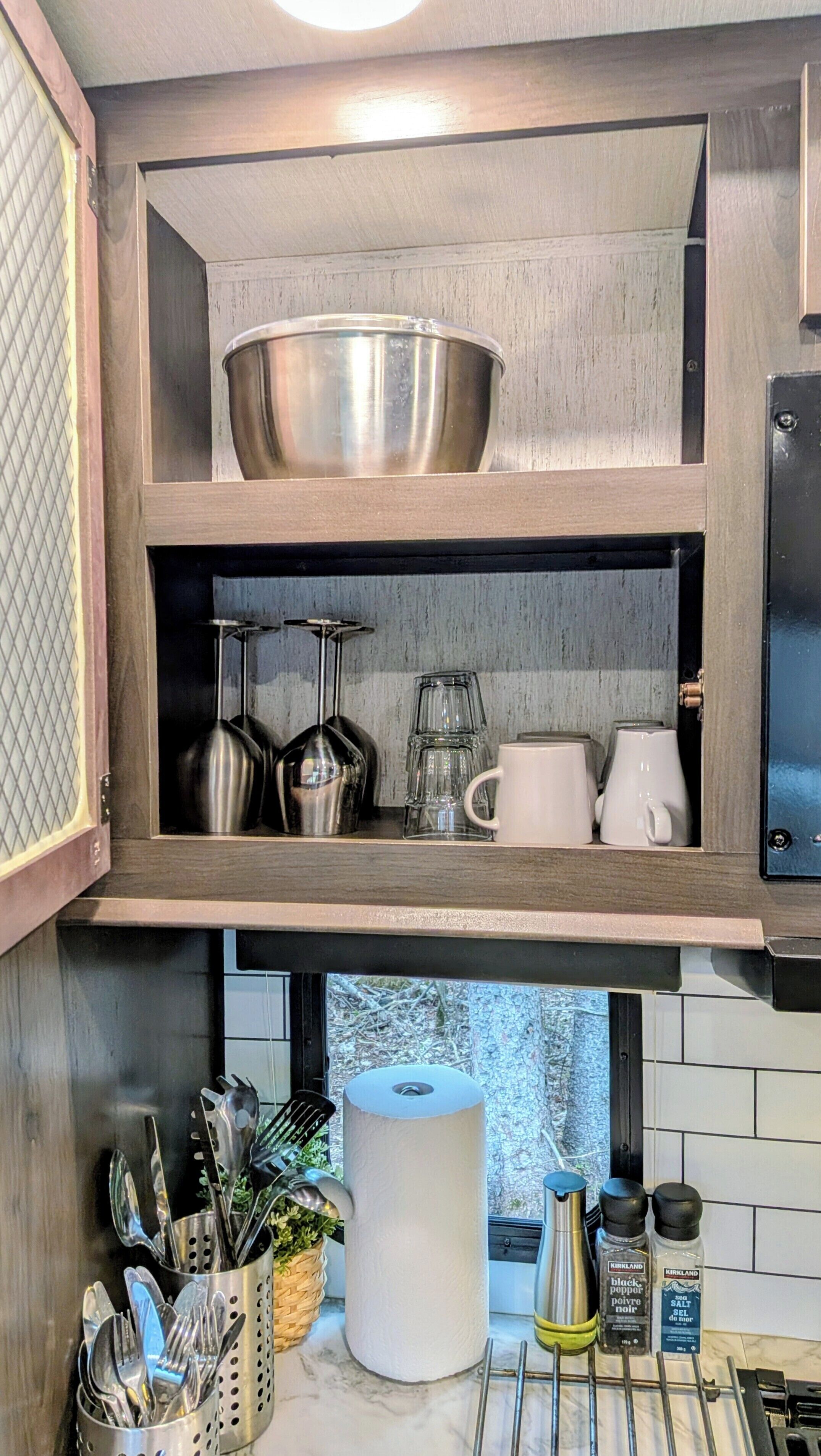 Eine Küche mit Holzschrank, Edelstahl-Schüssel, Glaswaren und Besteck.