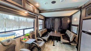 A cozy RV interior with seating, a table, and a TV screen.