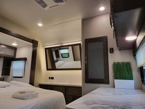 A modern hotel room with a large bed, a small desk, a mirror, and a window with blinds. - Furubekk • Nordic Spa RV • Pool • Sauna • Hot Tub • Ottawa (Mississippi Mills)