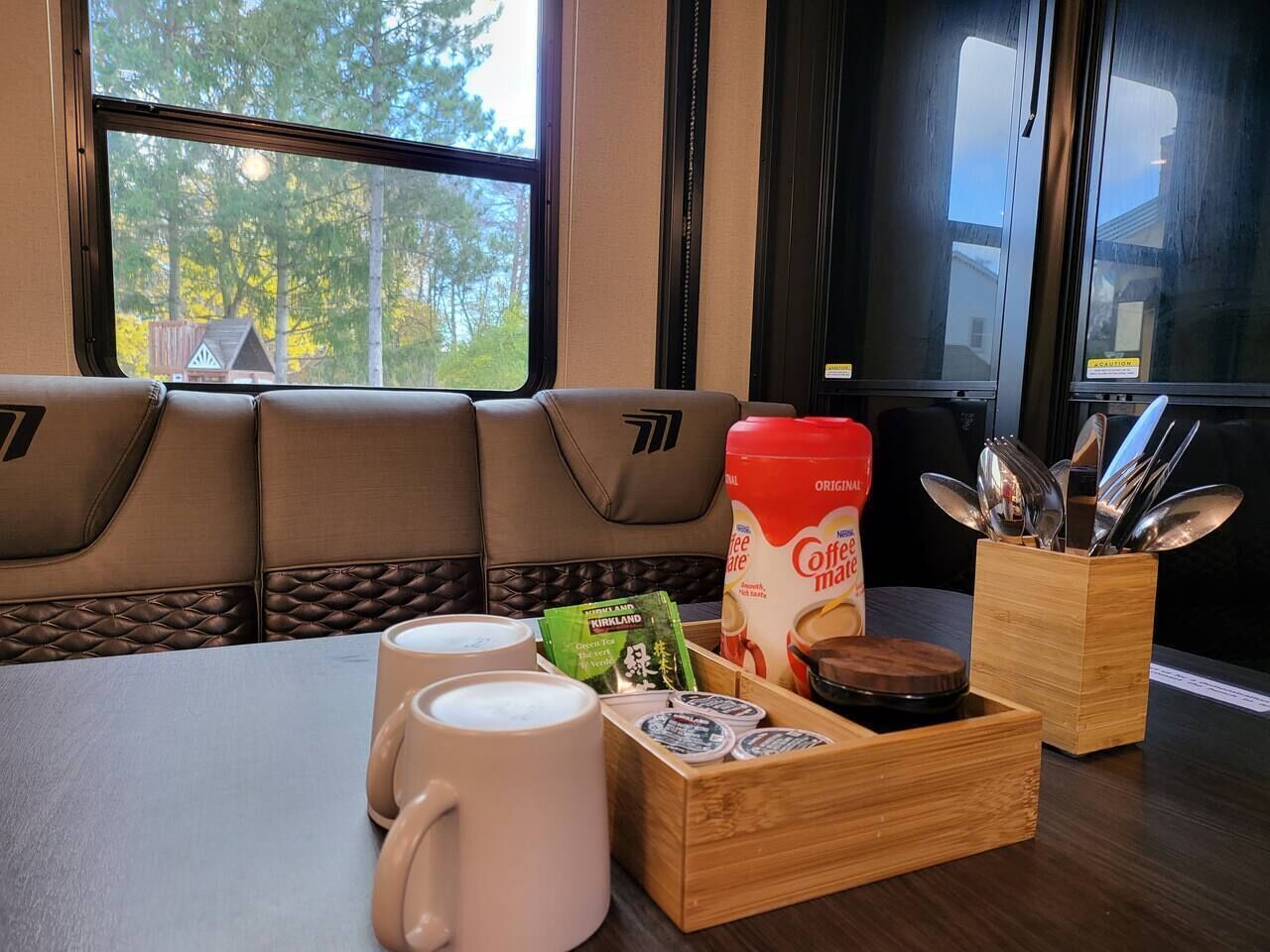 Ein Tisch mit einer Kaffeemaschine, Tassen und einer Packung Kaffeekapseln.