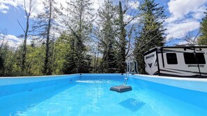 A swimming pool with a RV in the background.
