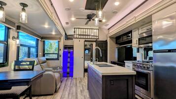 A modern RV interior with a kitchen, dining area, and a seating space with a view.
