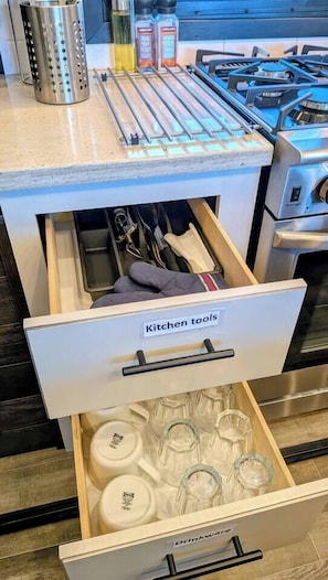 Un cajón de la cocina con la etiqueta 'Utensilios de cocina' que contiene diversos utensilios y utensilios de cocina.