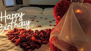 A bed with rose petals and a decorative headpiece, suggesting a romantic setting.