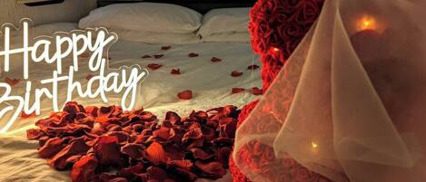 A bed with rose petals and a decorative headpiece, suggesting a romantic setting.