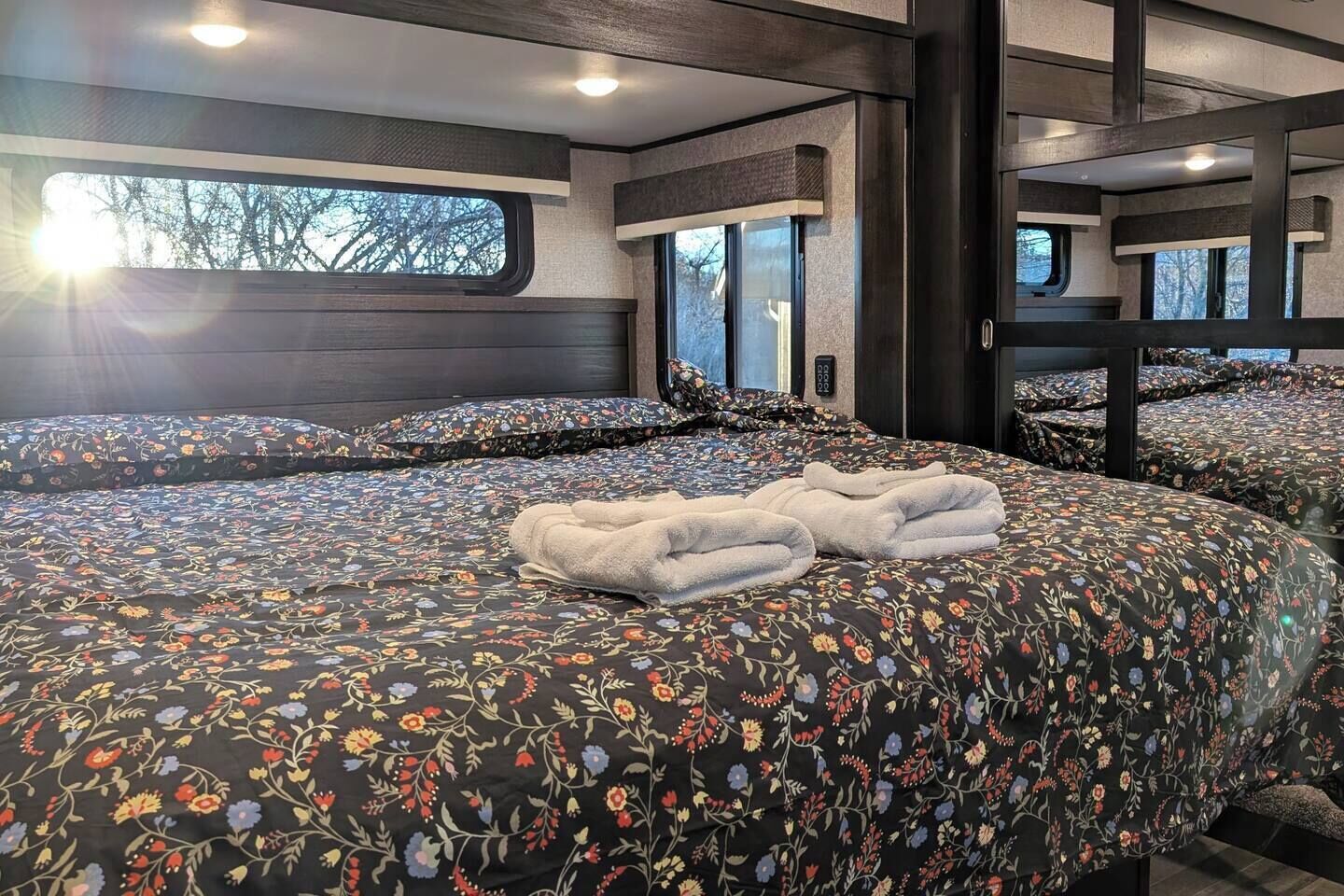 A bedroom with a large bed, multiple windows, and a view of the outdoors.