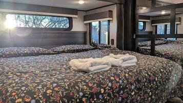 A bedroom with a large bed, multiple windows, and a view of the outdoors.