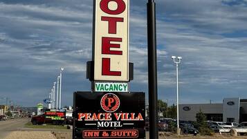 En skylt för ett motell med texten ”PEACE VILLA MOTEL” och en anmälan om att det finns lediga rum.