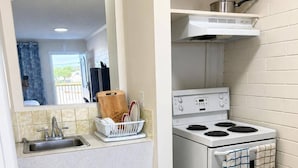 Cozinha compacta com pia, fogão e escorredor de louça.