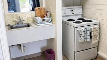 Une cuisine de taille réduite, équipée d’un évier, d’une cuisinière et d’un égouttoir à vaisselle.