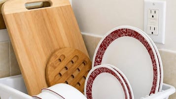Un égouttoir à vaisselle blanc avec des assiettes et une planche à découper en bois.