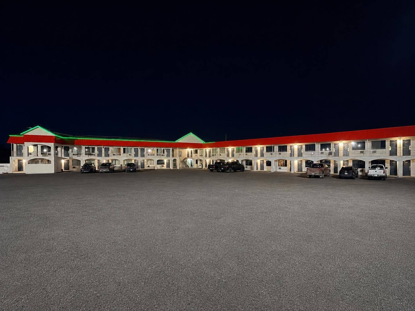Un motel comprenant plusieurs chambres, chacune dotée d’un balcon et d’une place de parking devant l’entrée.