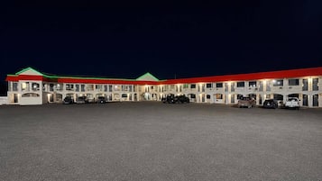 Un motel comprenant plusieurs chambres, chacune dotée d’un balcon et d’une place de parking devant l’entrée.