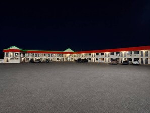 Een motel met verschillende kamers, elk voorzien van een balkon en een parkeerplaats ervoor.