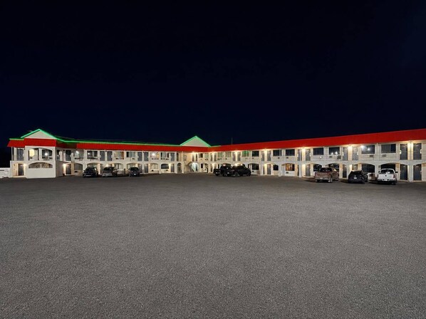 Un motel con varias unidades, cada una con un balcón y un espacio de estacionamiento al frente.