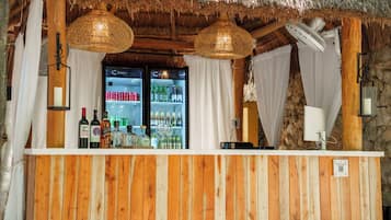A bar area with wooden paneling, a refrigerated display case, and hanging wicker lamps.