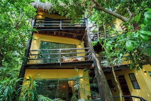 Un immeuble à plusieurs étages, doté de balcons et entouré d’une végétation luxuriante.