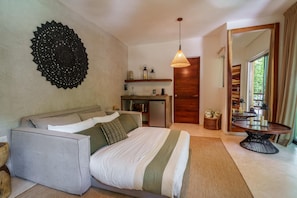 Een slaapkamer met een bed, een bank, een eettafel met kaarsen en een groot decoratief wandkunstwerk.