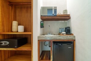 Une cuisine compacte équipée d’un four à micro-ondes encastré, d’un évier et d’un réfrigérateur.