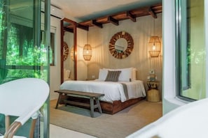 Een slaapkamer met een bed, nachtlampjes, een bankje en uitzicht door een glazen deur.